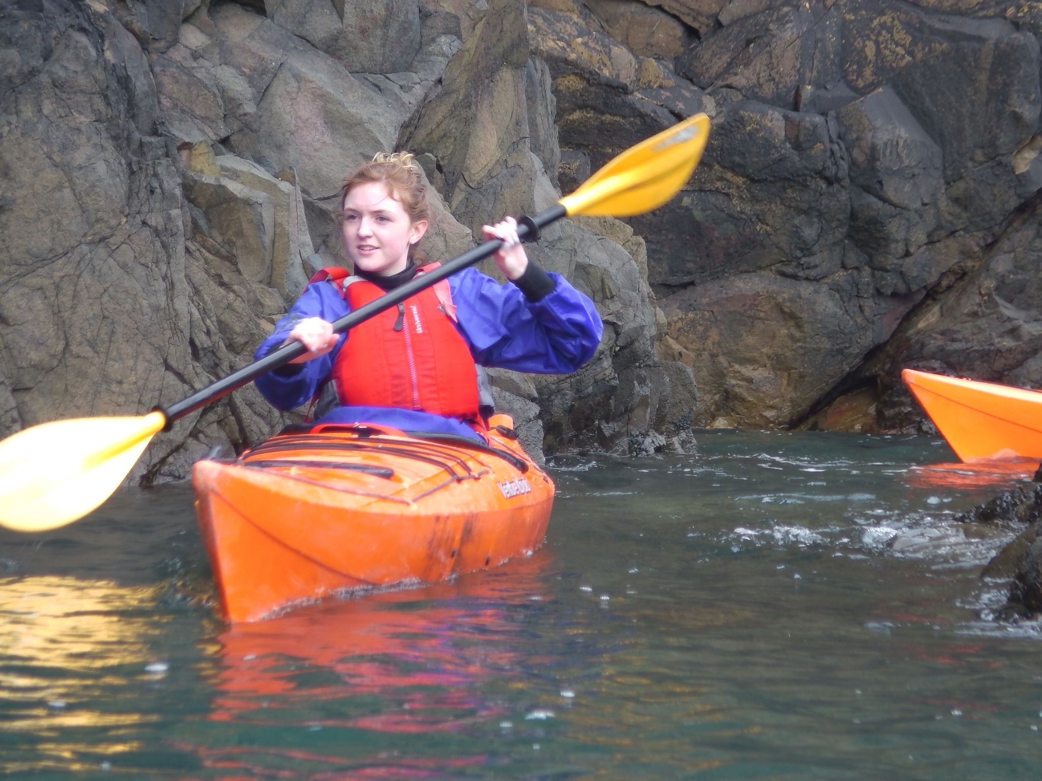 Beginner learning sea kayaking skills with a coach in Pembrokeshire.