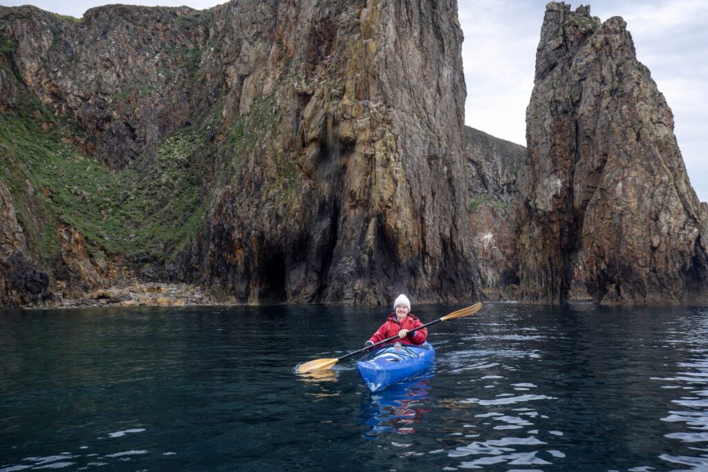 Kayaker paddling through Needle Rock arch