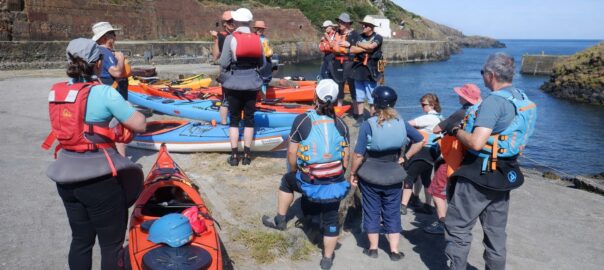 Experienced paddlers discussing sea conditions before launching in Pembrokeshire