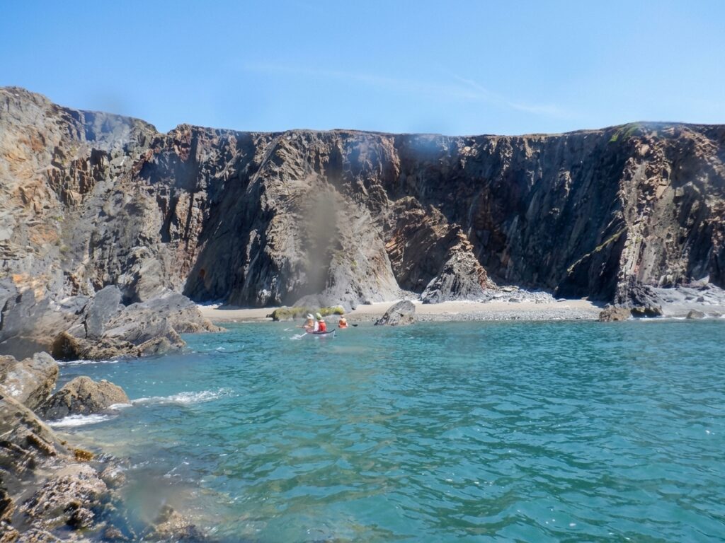 Sea kayakers paddling beneath dramatic cliffs on the Pembrokeshire coast