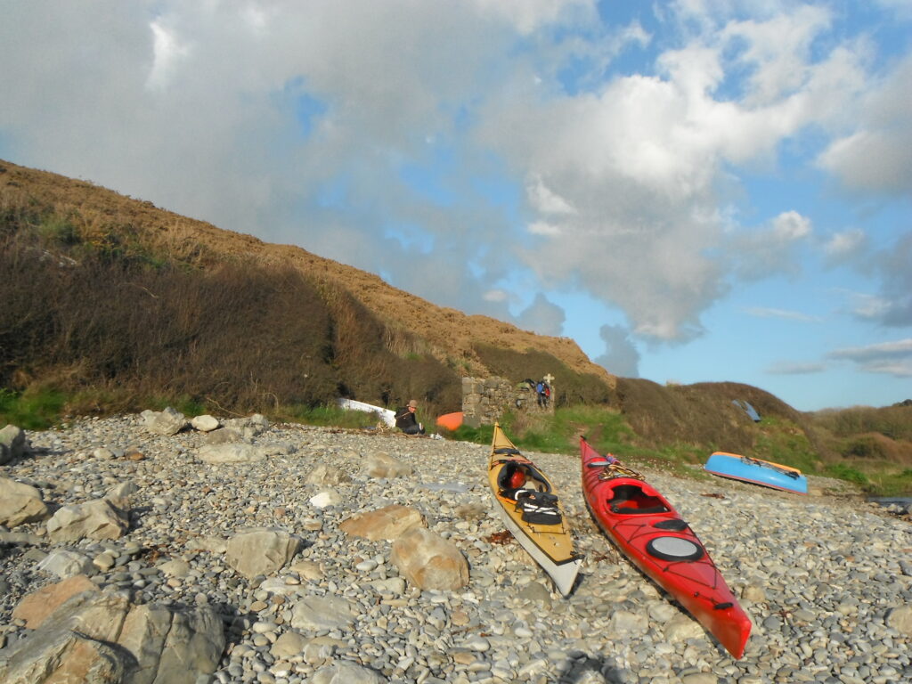 Loaded sea kayaks prepared for a multi-day Pembrokeshire sea kayaking expedition