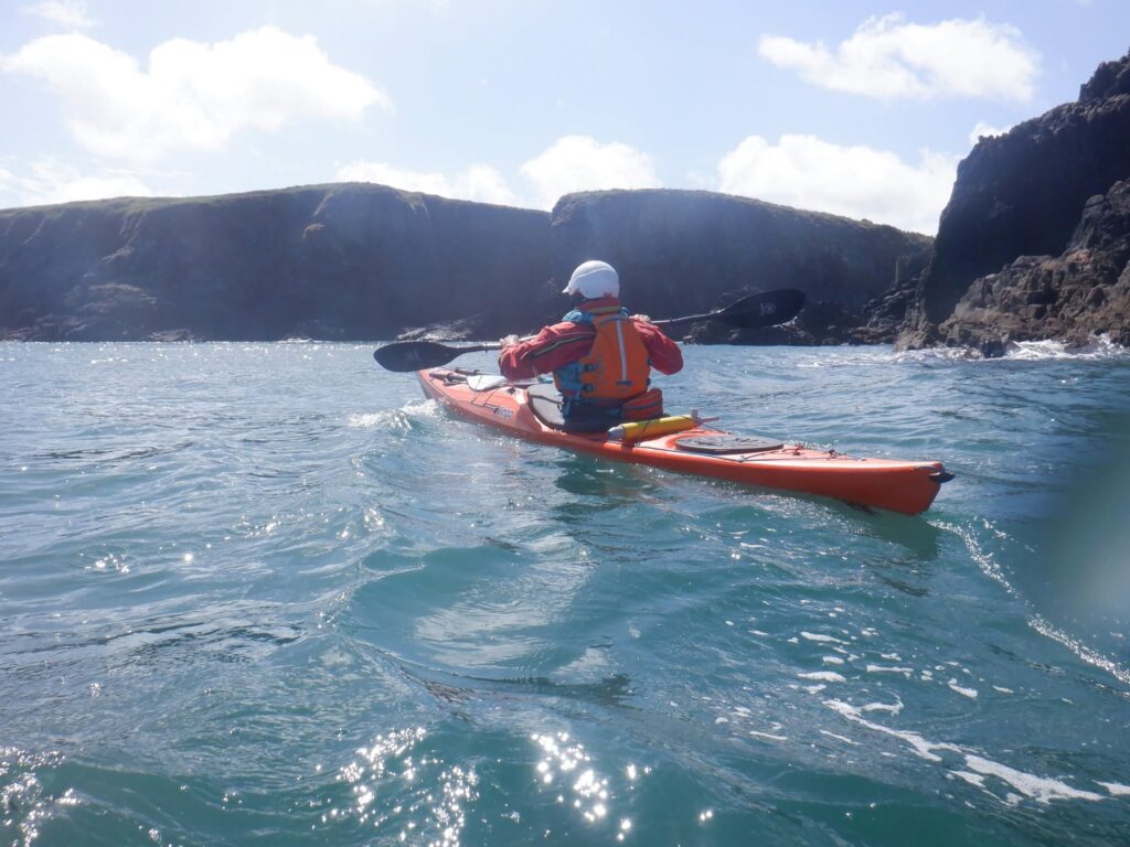 Sea kayaker paddling along the Pembrokeshire coastline during a long-distance expedition