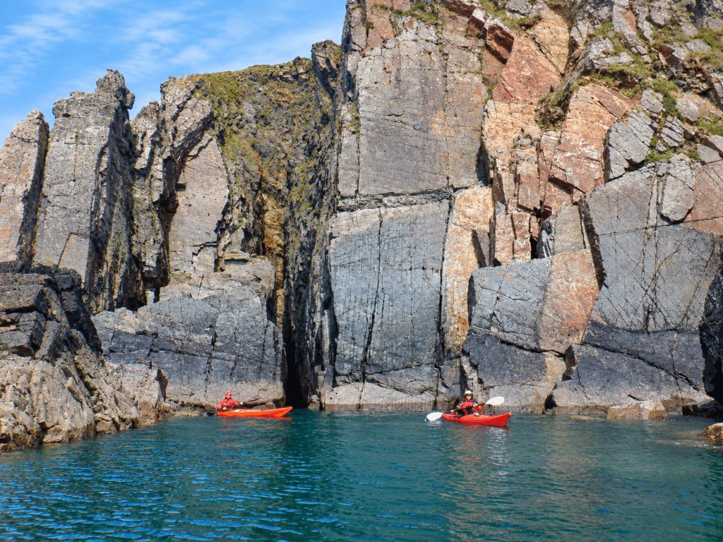 Sea kayakers with expedition equipment on the Pembrokeshire coast
