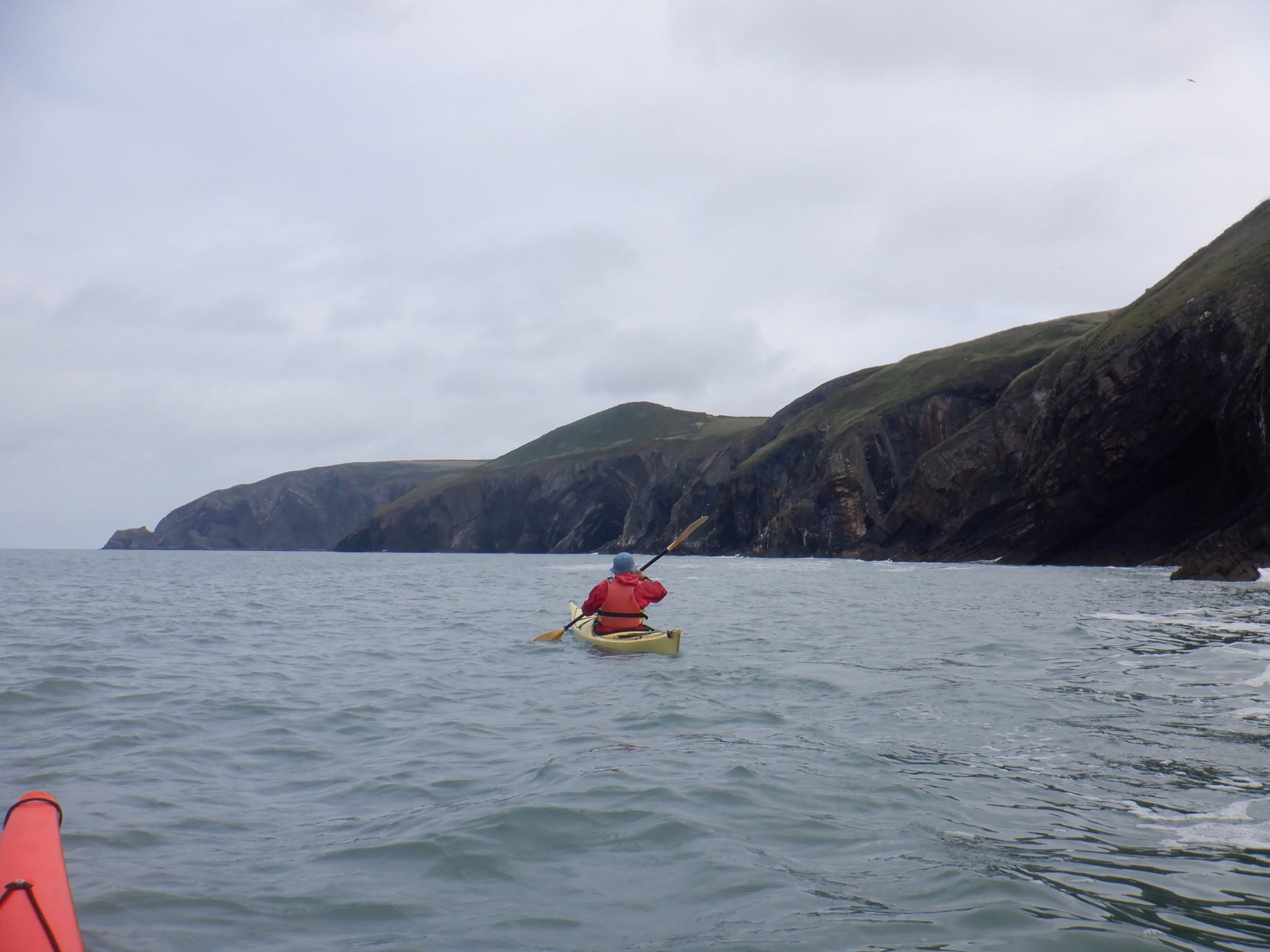 Sea kayaker paddling along the Pembrokeshire coast on a multi-day expedition