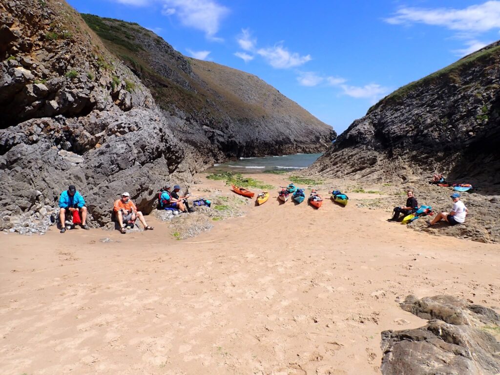 Sea kayakers stopping at a remote beach during a Pembrokeshire kayaking holiday