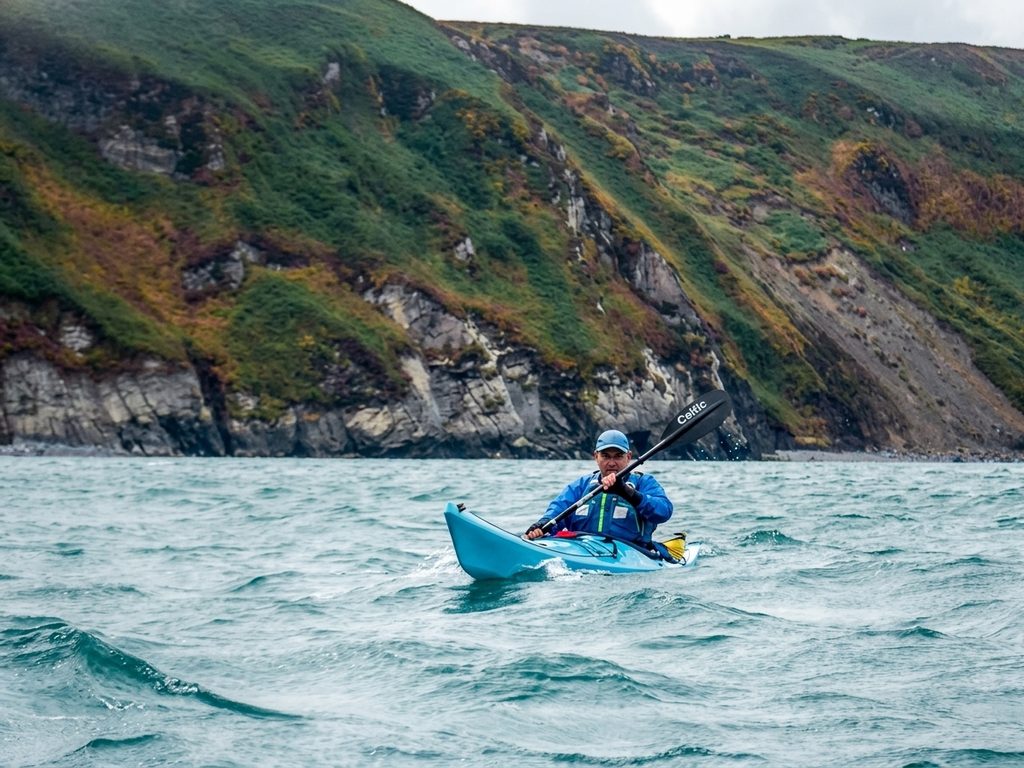 Sea kayaker paddling beneath cliffs on the Pembrokeshire coast