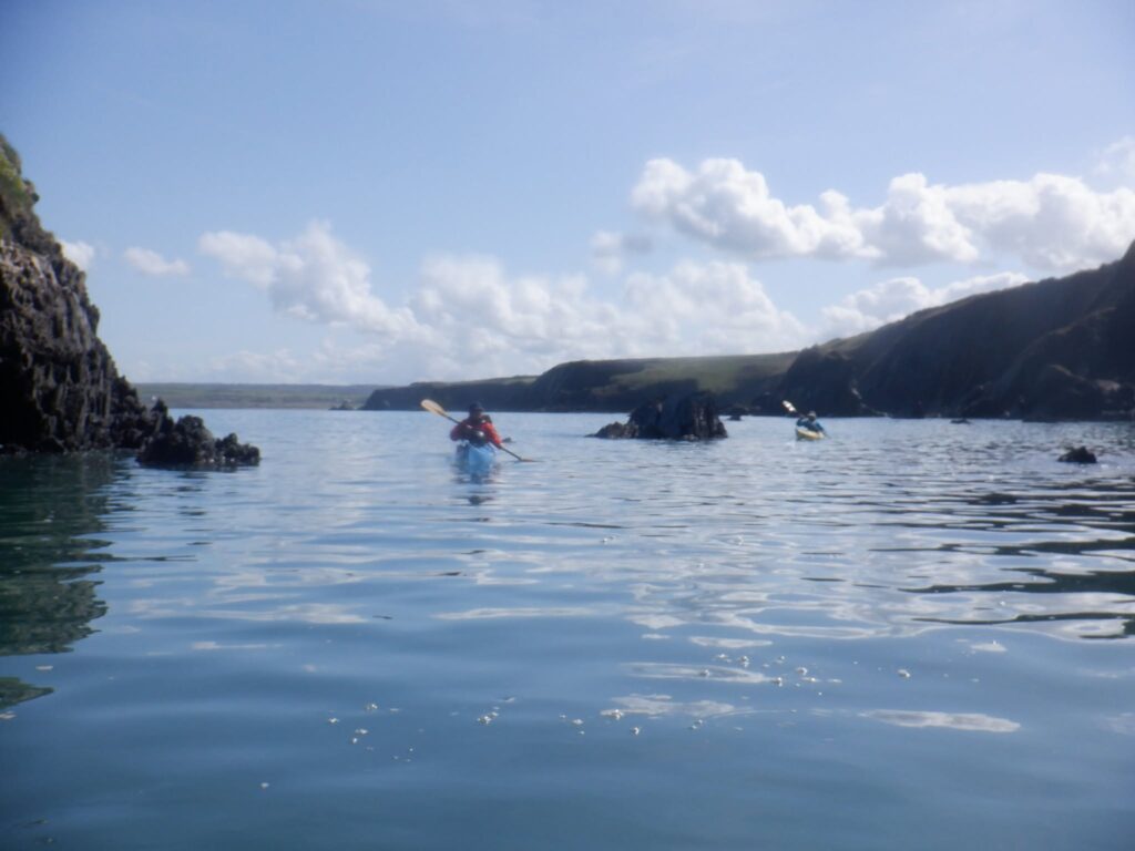 Small group of sea kayakers paddling along the Pembrokeshire coastline